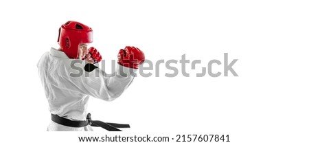 Flyer with portrait of young sportive man wearing white dobok, helmet and gloves practicing isolated over white background. Concept of sport, skills, workout, health. Hand-to-hand combat sport Royalty-Free Stock Photo #2157607841