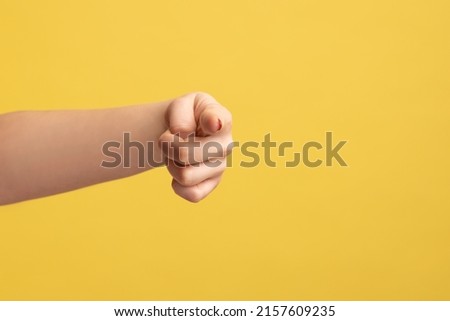 Closeup profile side view of woman hand finger pointing pointing direction to camera, choosing you. Indoor studio shot isolated on yellow background.