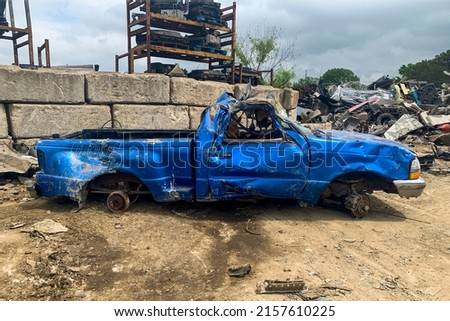 Side view of damaged blue pickup without wheels on the junkyard after car accident on a road, cemetery of cars, recycling broken automobiles Royalty-Free Stock Photo #2157610225