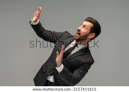 No, it's scary! Profile portrait of frightened shocked businessman in suit raising hands in fear, looking horrified and panicking, hiding from phobia. Indoor studio shot isolated on grey background  Royalty-Free Stock Photo #2157611613