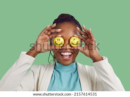 Always keep smiling, look for the good and stay optimistic. Studio shot of a happy lady Positive African American woman covers her eyes holding two smiley faces in hands Royalty-Free Stock Photo #2157614531