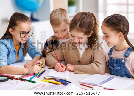 Smart kids pupils   writing down data into notebook  while communicating with classmates during lesson at school in daytime Royalty-Free Stock Photo #2157615679