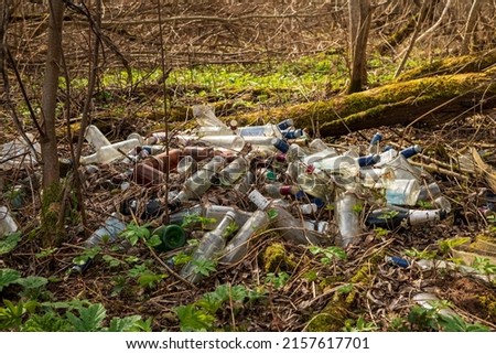 Landfill of glass bottles and garbage on the ground in the forest. The concept of environmental pollution. Royalty-Free Stock Photo #2157617701