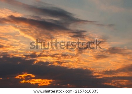 Beautiful dramatic summer evening sky with beige and orange cumulus clouds and sun rays. Panoramic horizontal cloudscape. High-resolution photography. Design element. Copy space.
