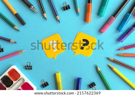 Many stationary supplies on blue background with question marks. Office accessories flat lay. First September, back to school, education, creativity concept. Pens, pencils and paints with copyspace 