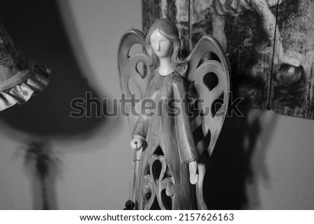Black and white photo of a wooden angle figure with carved wings