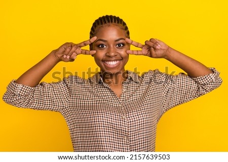Photo of funny pretty lady dressed checkered shirt showing v-signs cover eyes isolated yellow color background