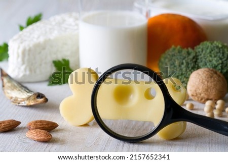 Bone shaped cheese, magnifier and bone strengthening foods products, concept osteoporosis and prevention Royalty-Free Stock Photo #2157652341