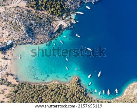 Aerial drone footage of daily tour boats and private yachts anchored in Cennet Bay, located in Selimiye village of Marmaris District of Muğla City, Turkey. Royalty-Free Stock Photo #2157655119