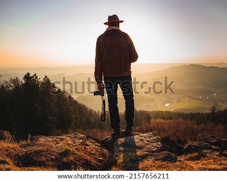 A German male photographer with camera taking photos of landscape at sunset