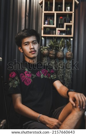Picture of a male model wearing a black t-shirt with a rose pattern