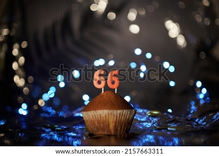 Tasty fresh homemade vanilla cupcake with number 66 sixty six on aluminium foil and blurred bright background in minimalistic style. Digital gift card birthday concept. High quality image