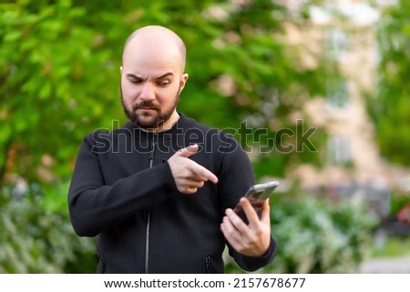 Handsome young man with a beard using his phone with surprise and joy