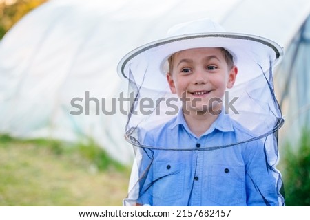 Close up portrait of cute preteen boy in beekeeper protective suit outdoor. Beekeeping concept