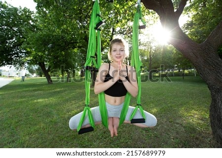 Little girl doing yoga exercises with a hammock in the park