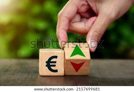 Hand spinning wooden dice and changes the direction of an arrow symbolizing that the value of the Euro currency icon is going up (or lower), The concept of the growth currency of Euro.                