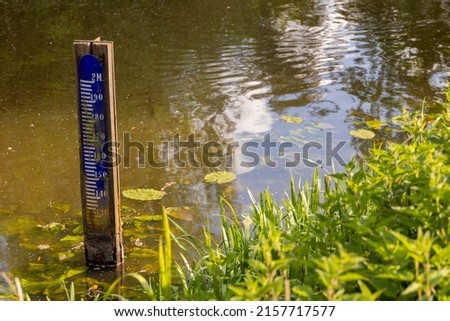Water level depth meter, gauge or staff. Extreme low water level in river. Global warming. Shortage, scarcity or lack of water or rain due to hot temperatures. Climate change crisis.Co2, part of serie Royalty-Free Stock Photo #2157717577