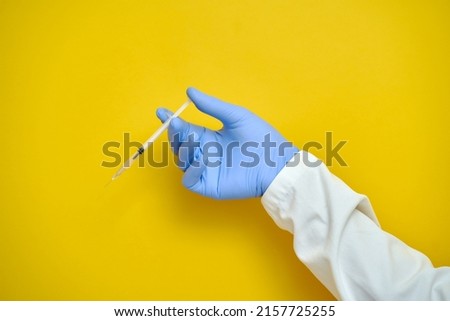 Laboratory hand in medical gloves vaccine treatment research on a yellow background