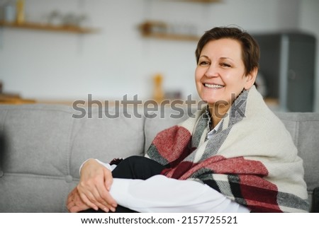 portrait of senior woman at home on sofa with plaid