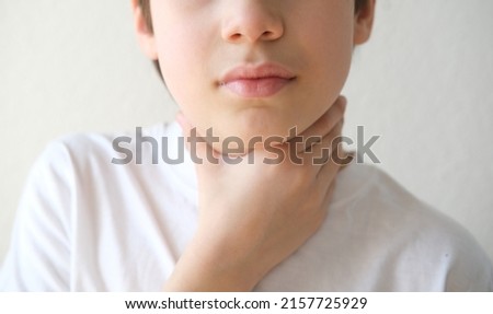 close-up of hands of child holds throat, boy of 10 years old is sick, concept of children's health, pediatrics, thyroid inflammation, Overview of the Thyroid Gland, loss of voice Royalty-Free Stock Photo #2157725929