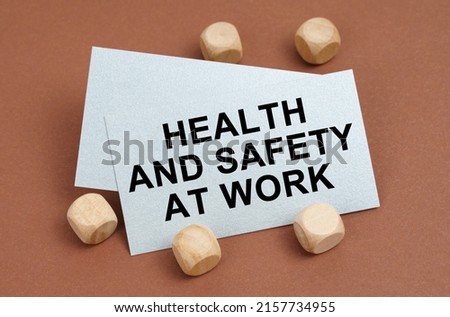 The concept of industrial safety. On a brown surface, wooden cubes and a business card with the inscription - Health And Safety At Work