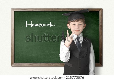 Cheerful little boy on blackboard. Looking at camera