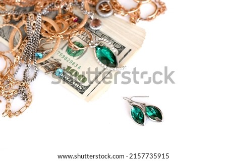 Many expensive golden and silver jewerly rings, earrings and necklaces with big amount of US dollar bills on white background. Pawnshop or jewerly shop concept Royalty-Free Stock Photo #2157735915