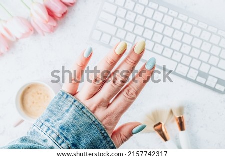 Beautiful groomed female hands with pastel blue and yellow nails. Manicure beauty salon concept. Empty place for text. Top view