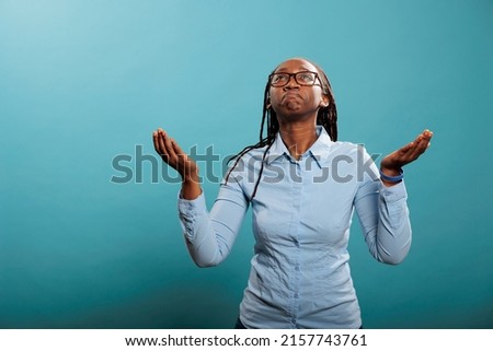 Religious and spiritual young person praying for a better and forgiving world. Faithful african american woman with palms faced to sky pleading and begging to have her sins forgiven. Royalty-Free Stock Photo #2157743761
