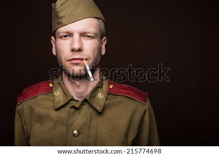 Russian soldier smoking cigarette. Studio portrait isolated on brown background 