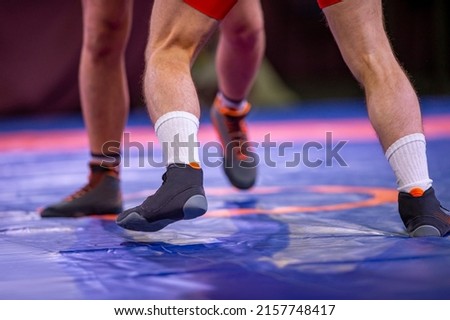 Greco-Roman wrestling. Two sportsmens wrestlers in red and blue uniform wrestling against wrestling carpet