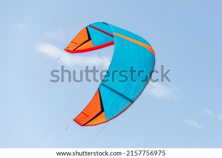 Close-up detail one bright blue orange kitesurf wings kite equipment fly against clear sky t on bright sunny day against at kiter riding surf school camp. Active travel sport concept Royalty-Free Stock Photo #2157756975