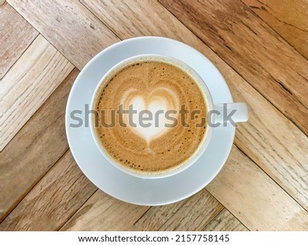 A cup of coffee latte On a wooden table. A mug of flat white coffee on a wooden background. Coffee art. Heart flower shape latte art. Copy space