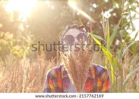 Defocus teen or preteen girl walking on nature background. Little kid girl holding bunch of pampas grass and blowing. Blurred reed on foreground. Hipster, generation z. Sunny, sunset. Out of focus.