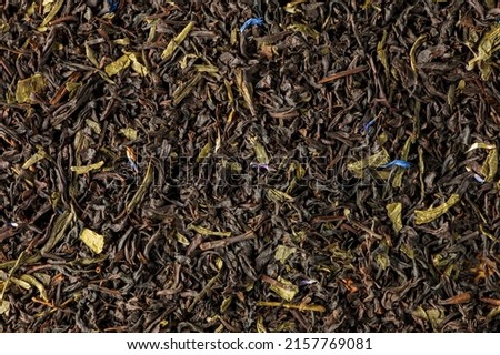 A blend of Ceylon black and green teas. Background of leaf tea with cornflower and calendula petals. View from above.