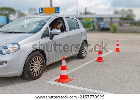 Girl loooking at cones trying to orientate at parking at practise for driving test.