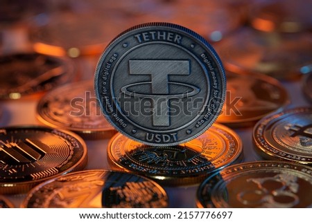 Tether USDT Cryptocurrency Physical Coin placed on crypto altcoins and lit with orange and blue lights in the dark Backgrond. Macro shot. Selective focus. Royalty-Free Stock Photo #2157776697