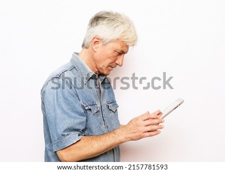 Lifestyle, tehnology and old people concept: Senior man using digital tablet. Mature gray-haired male wearing jeans shirt using portable computer over white background.