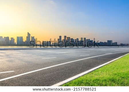 Asphalt road and modern city skyline with buildings in Hangzhou at sunset, China.