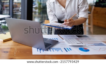 Businesswoman analyzing investment charts with calculator laptop. Accounting and technology in the office. Asian Business using laptop accountant Documents data partner deal in the workplace