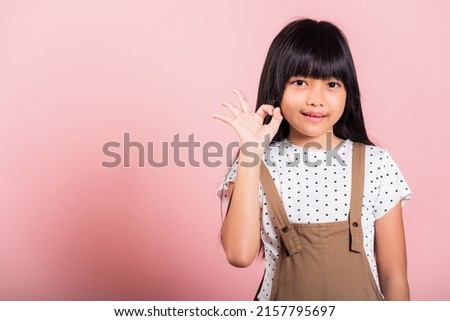 Asian little kid 10 years old showing OK gesture in sign language at studio shot isolated on pink background, Happy child girl lifestyle making Okey fingers
