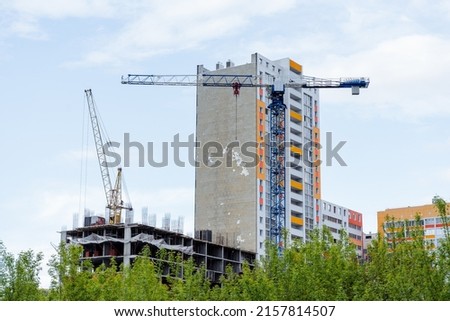 The construction of a residential building, a high-rise construction crane works at a height, a construction site, an apartment building, a residential quarter. High quality photo