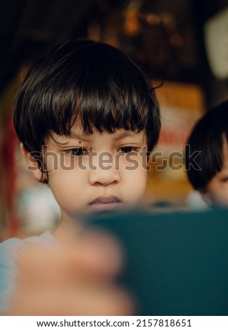2 cute Asian kids sitting on the dining table with mobile phones ,Internet phone addictive concept