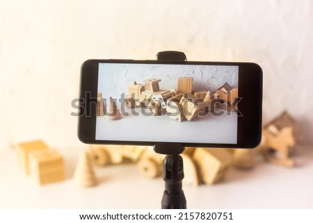 Eco blogger filming video about wooden kids toys. Smart phone taking pictures of blocks and bricks. Blog about Minimalism for parents.