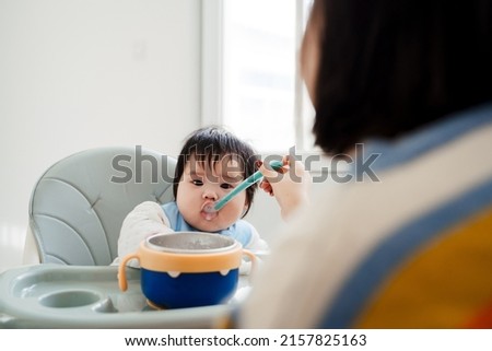 6 month old baby girl is eating fruit Royalty-Free Stock Photo #2157825163