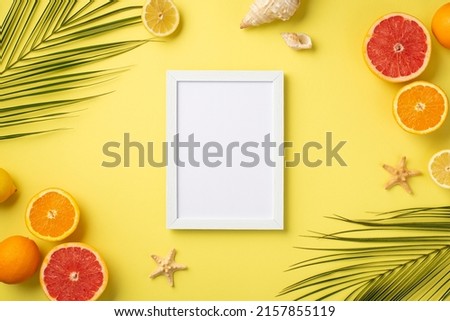 Summer weekend concept. Top view photo of white photo frame tropical fruits cut oranges lemons grapefruits shells starfishes and green palm leaves on isolated yellow background with blank space