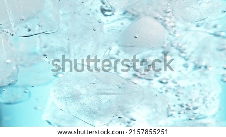 Close up of ice cubes underwater, blue background. Freeze motion of flowing ice in water.