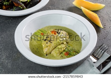 Closeup view of cod with asparagus in white plate over grey concrete background 
