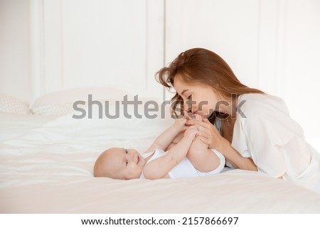 mom kisses the baby's legs at home in the bedroom