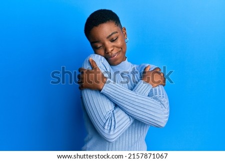 Young african american woman wearing casual clothes hugging oneself happy and positive, smiling confident. self love and self care  Royalty-Free Stock Photo #2157871067